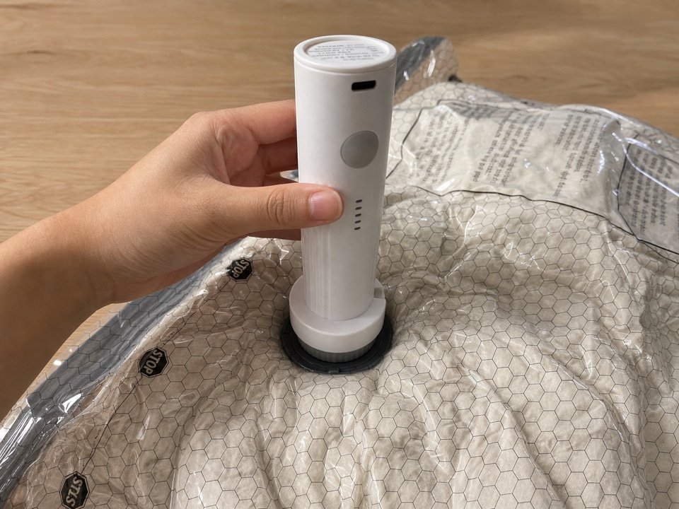White portable pump attached to the round valve of a compression bag